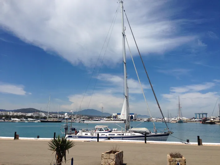 Bella Rose Yacht Photos Pics 2006 Hallberg-Rassy 48 yacht docked in a scenic marina under a blue sky.