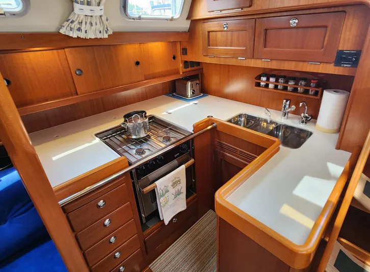 Bella Rose Yacht Photos Pics Luxurious 2006 Hallberg-Rassy 48 yacht kitchen with wooden cabinetry and modern appliances.