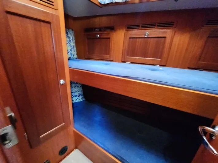 Bella Rose Yacht Photos Pics Interior of 2006 Hallberg-Rassy 48 yacht with wooden bunk beds and blue cushions.
