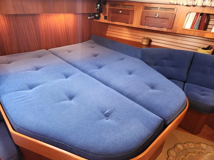 Bella Rose Yacht Photos Pics Cozy cabin interior of 2006 Hallberg-Rassy 48 yacht with blue cushions and wooden accents.