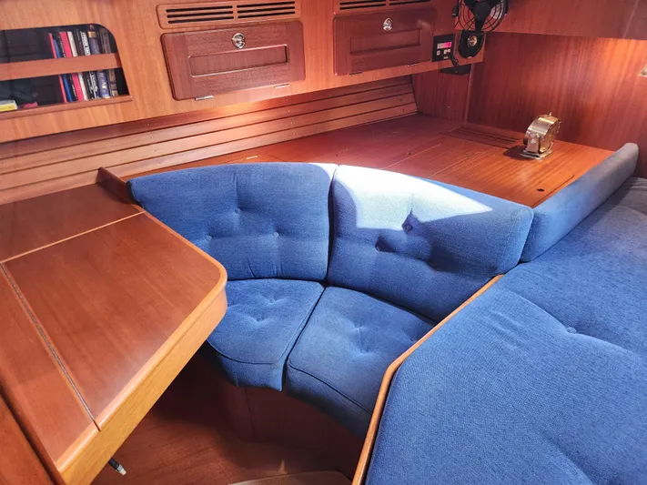 Bella Rose Yacht Photos Pics Interior of 2006 Hallberg-Rassy 48 yacht with blue cushioned seating and wooden cabinetry.