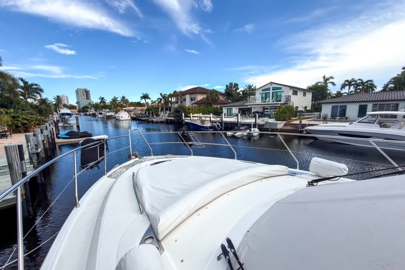  Yacht Photos Pics 2015 Beneteau Gran Turismo 49 yacht docked in a scenic canal with waterfront homes.