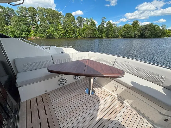  Yacht Photos Pics Luxurious 2017 Sea Ray L590 yacht deck with seating and table, overlooking serene lake and trees.