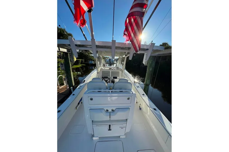  Yacht Photos Pics 2024 Invincible 33 Open Fisherman boat with flags, docked in sunlight.