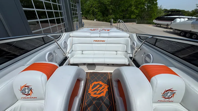  Yacht Photos Pics 2003 Fountain 47 Lightning boat interior with white and orange seating, docked near a marina.
