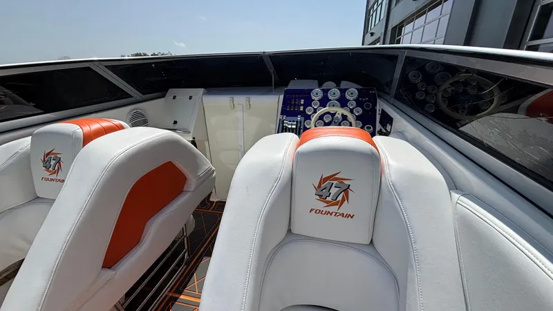  Yacht Photos Pics 2003 Fountain 47 Lightning boat interior with white and orange seating, dashboard view.