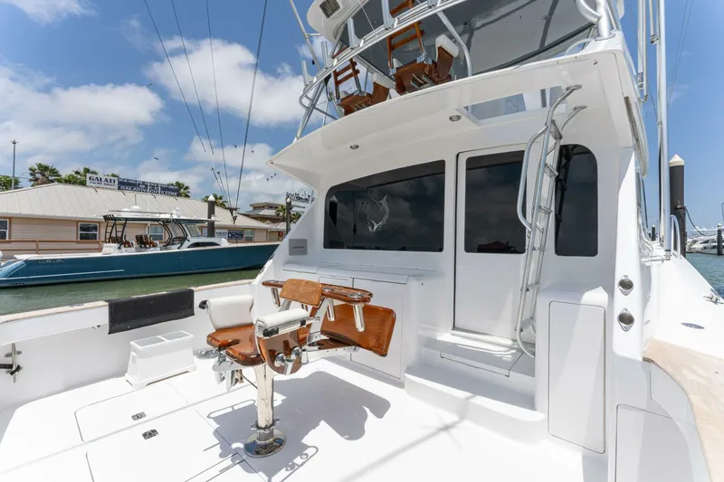 Wound Tight Yacht Photos Pics 2004 Viking 48 Convertible yacht with fishing chair and ladder, docked under blue sky.