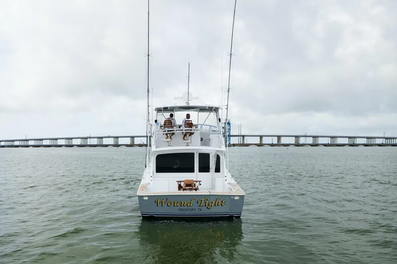 Wound Tight Yacht Photos Pics 2004 Viking 48 Convertible boat on water near bridge, overcast sky.