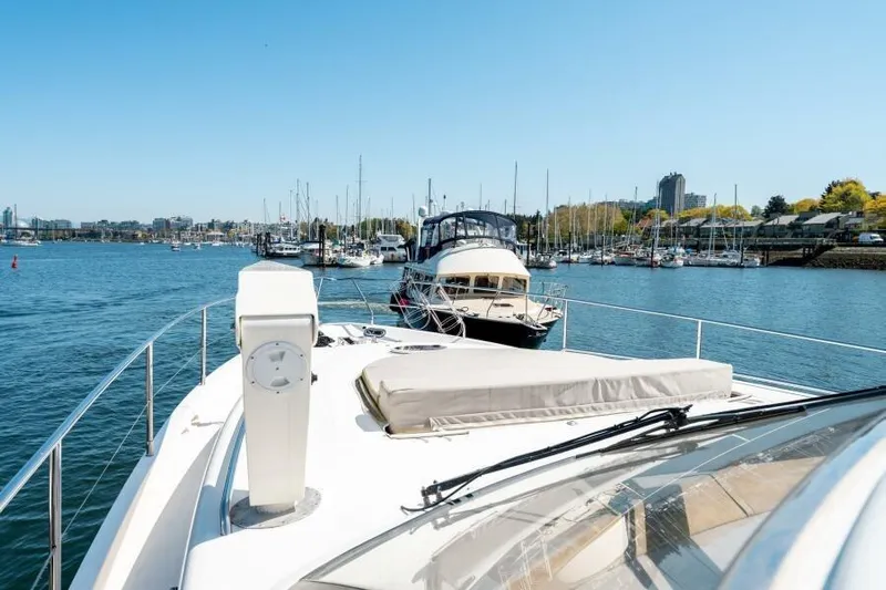 Jugni Yacht Photos Pics 2003 Viking Princess 65 yacht docked in a sunny marina with cityscape background.