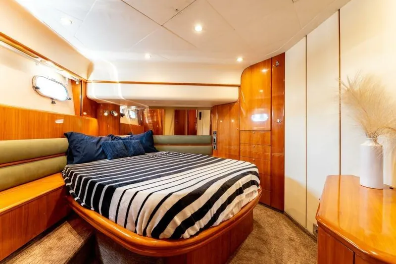 Jugni Yacht Photos Pics Luxurious 2003 Viking Princess 65 yacht bedroom with striped bedding and elegant wood finishes.