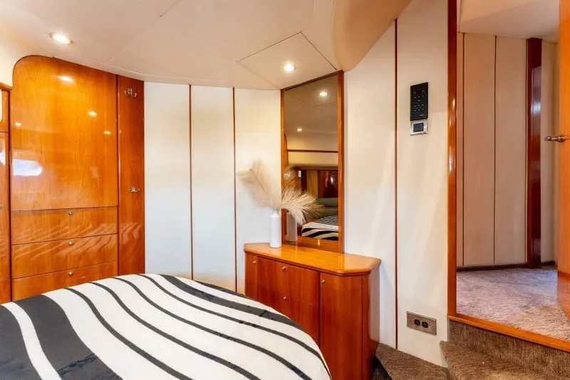 Jugni Yacht Photos Pics Luxurious 2003 Viking Princess 65 yacht bedroom with elegant wood finishes and striped bedding.