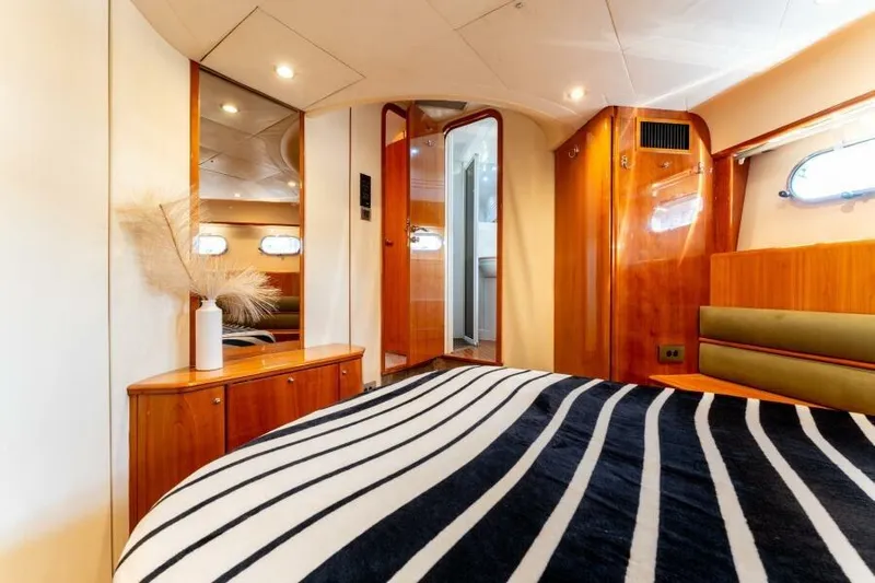 Jugni Yacht Photos Pics Luxurious 2003 Viking Princess 65 yacht bedroom with elegant wood finishes and striped bedding.