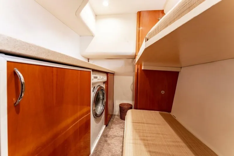 Jugni Yacht Photos Pics Laundry area with wooden cabinets and washer in 2003 Viking Princess 65 yacht.