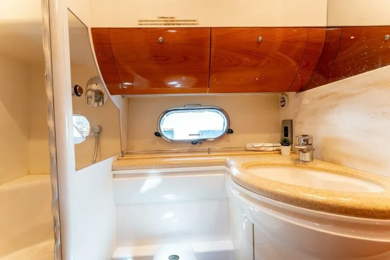 Jugni Yacht Photos Pics Luxurious bathroom interior of 2003 Viking Princess 65 yacht with wood accents and porthole window.