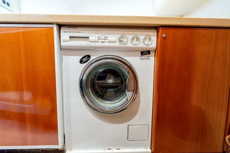 Jugni Yacht Photos Pics Washing machine in 2003 Viking Princess 65 yacht interior, surrounded by wooden cabinetry.
