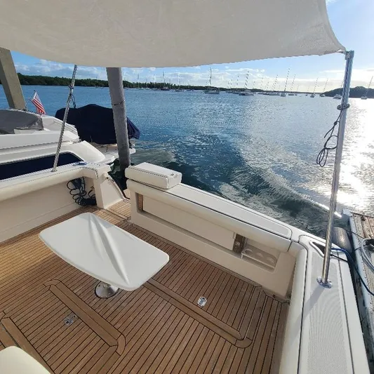 Blue Meridian Yacht Photos Pics 2003 Tiara Yachts 3800 Open, teak deck, docked by calm waters under a sunny sky.