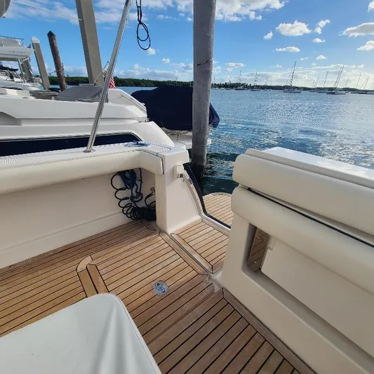 Blue Meridian Yacht Photos Pics 2003 Tiara Yachts 3800 Open, teak deck, docked by calm waters under blue sky.