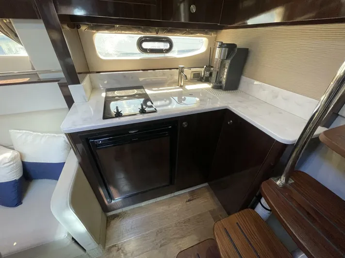 Tin Cup Chalice Yacht Photos Pics 2019 Sea Ray Sundancer 350 Coupe interior kitchen with stove, sink, and compact fridge.