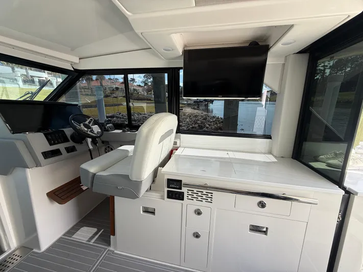  Yacht Photos Pics Interior of 2022 Regal 36 Grande Coupe with helm, seating, and mounted TV.