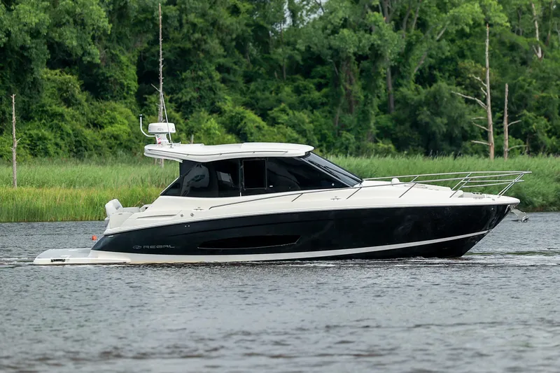  Yacht Photos Pics 2022 Regal 36 Grande Coupe cruising on a river with lush green background.