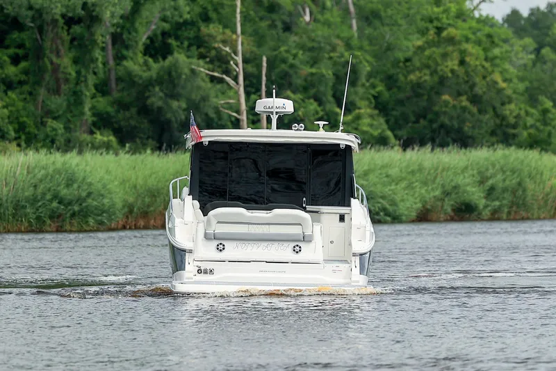  Yacht Photos Pics 2022 Regal 36 Grande Coupe cruising on a river with lush green surroundings.