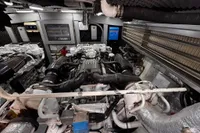 Engine room of a 2001 Pershing 65 yacht, showcasing complex machinery and components.
