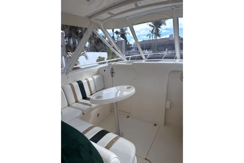 Summit Yacht Photos Pics 2004 Intrepid 377 Walkaround interior with seating and table, featuring large windows and palm tree view.