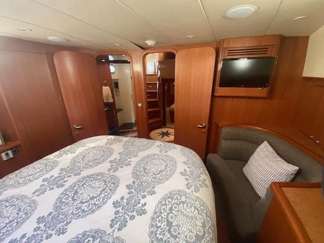 "conumdrum" Yacht Photos Pics Luxurious bedroom in 2007 Regency Yachts 670 Pilothouse with wood paneling and TV.