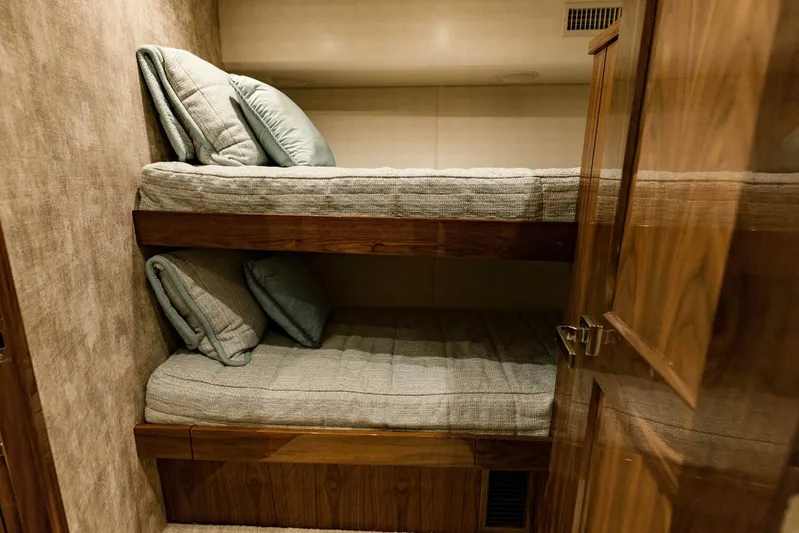 Sari Victoria Yacht Photos Pics Bunk beds in a 2020 Viking 72 yacht cabin, featuring cozy bedding and wooden finishes.