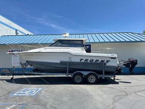 1992 Bayliner 2359 Trophy boat on trailer, parked outside a building under clear blue sky.