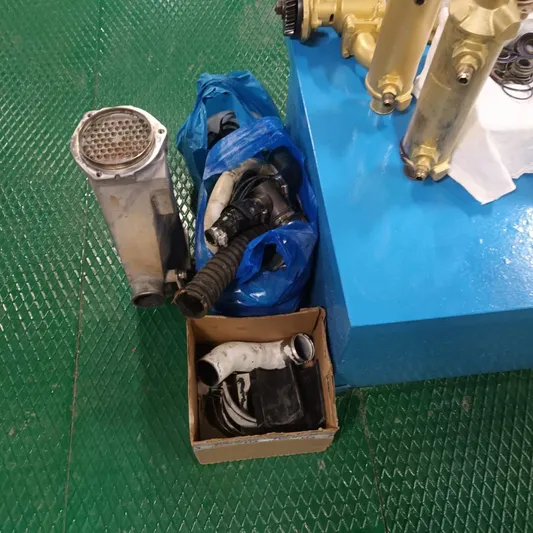 Three Wishes Yacht Photos Pics Assorted mechanical parts on green floor, including hoses and metal components, near blue platform.