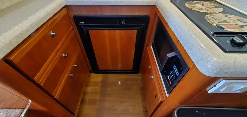 Mai Time Yacht Photos Pics 2001 Bertram 390 Convertible kitchen with wood cabinets, compact fridge, and microwave.
