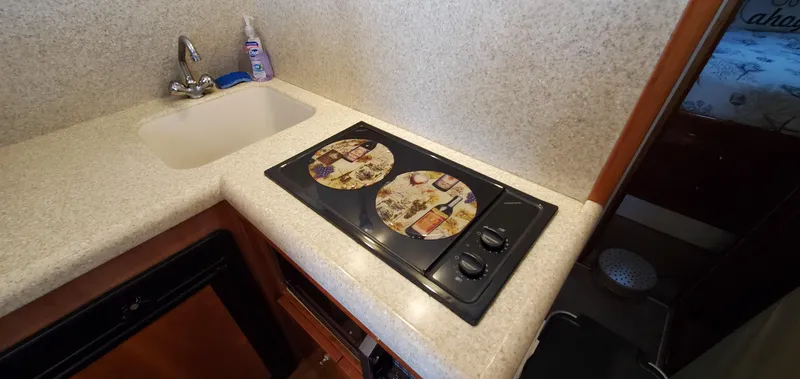 Mai Time Yacht Photos Pics Compact kitchen area in a 2001 Bertram 390 Convertible yacht with sink and stove.
