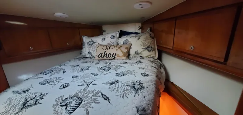 Mai Time Yacht Photos Pics Cozy cabin bedroom in 2001 Bertram 390 Convertible with nautical-themed bedding and wooden cabinets.