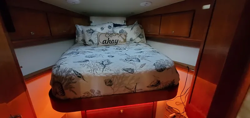 Mai Time Yacht Photos Pics Cozy bedroom in 2001 Bertram 390 Convertible yacht with nautical-themed bedding and warm lighting.