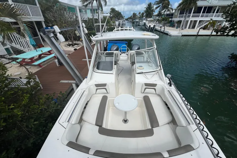  Yacht Photos Pics 2020 World Cat 296 DC boat docked by waterfront homes, featuring spacious seating and table.