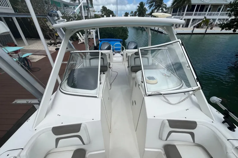  Yacht Photos Pics 2020 World Cat 296 DC boat docked by waterfront homes, featuring dual consoles and seating.