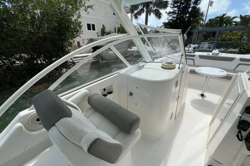  Yacht Photos Pics 2020 World Cat 296 DC boat interior with seating and table, surrounded by lush greenery.