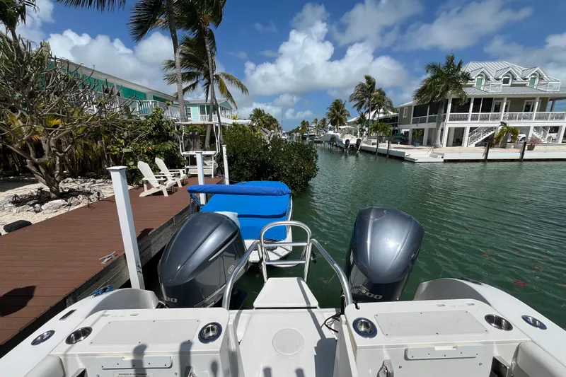  Yacht Photos Pics 2020 World Cat 296 DC boat docked by waterfront homes under a sunny sky.