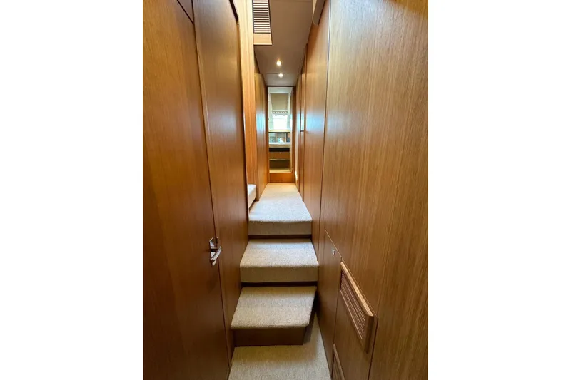  Yacht Photos Pics Interior hallway of 2014 Fairline Squadron 65 yacht with wooden paneling and carpeted steps.