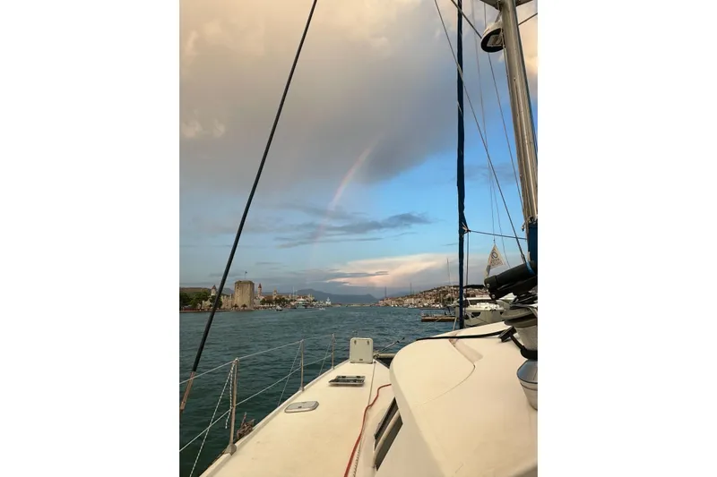  Yacht Photos Pics Sailing on a 1998 Fountaine Pajot Bahia 46 catamaran under a rainbow in a scenic harbor.