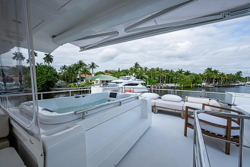 Lucky 7 Yacht Photos Pics Luxurious 2017 Azimut 80 yacht deck with jacuzzi and seating, overlooking a serene waterfront.