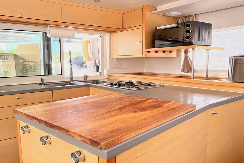  Yacht Photos Pics Modern kitchen interior of 2018 Lagoon 450S yacht with wooden cabinetry and appliances.