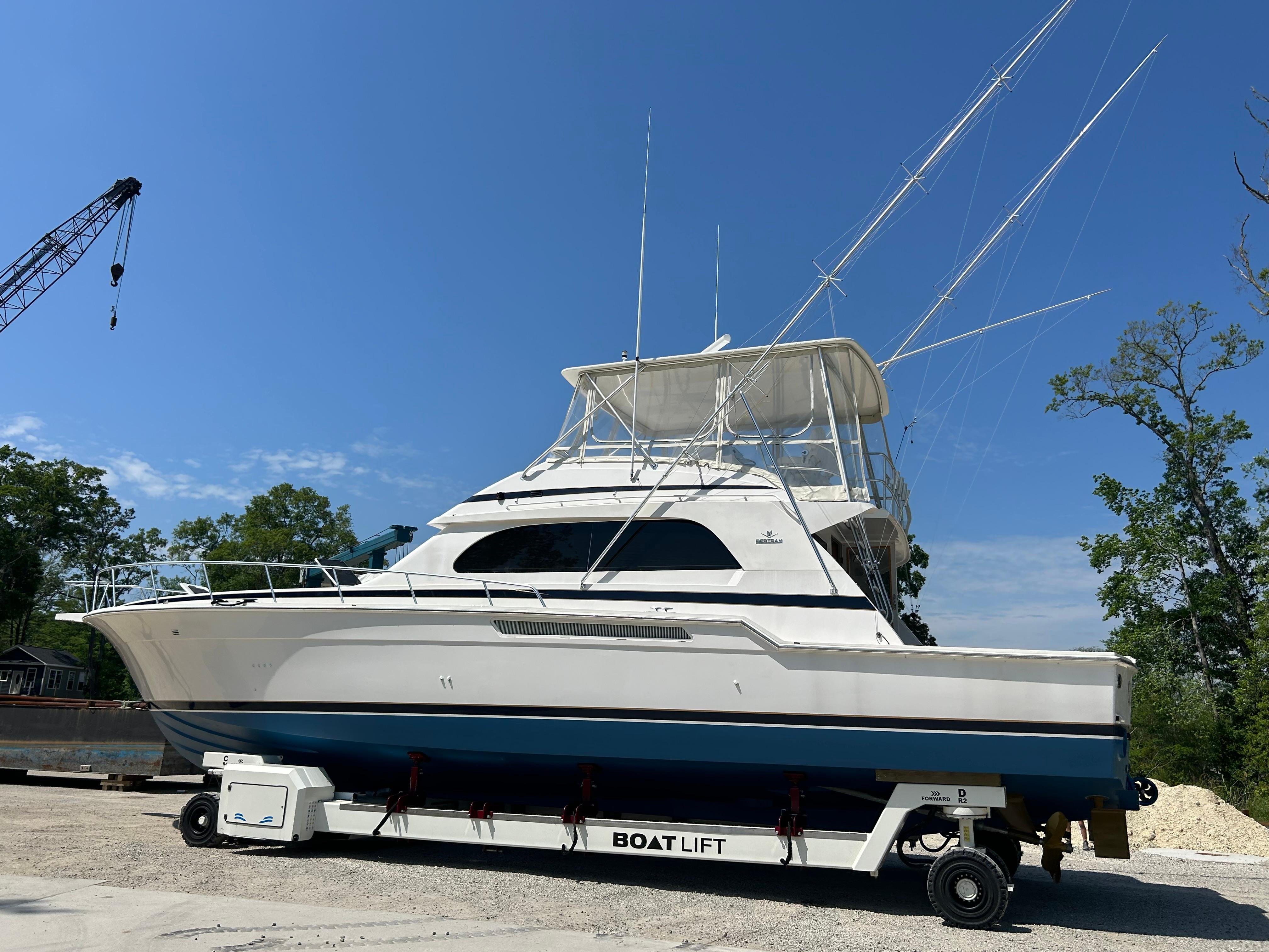1999 Bertram 60 Convertible yacht on a boat lift, clear sky background.