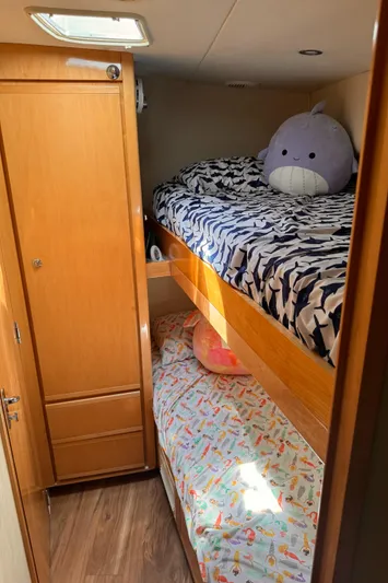 Satisfaction Yacht Photos Pics Bunk beds in the 1999 Bertram 60 Convertible cabin with plush toys and wooden cabinetry.