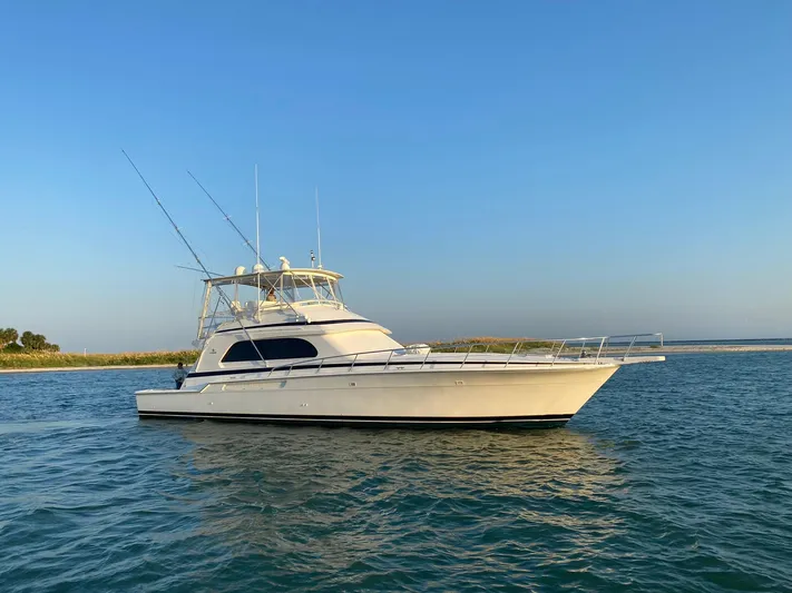 Satisfaction Yacht Photos Pics 1999 Bertram 60 Convertible yacht on calm waters under clear blue sky.