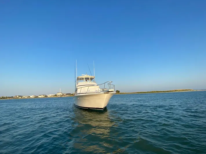 Satisfaction Yacht Photos Pics 1999 Bertram 60 Convertible yacht on calm waters under clear blue sky.