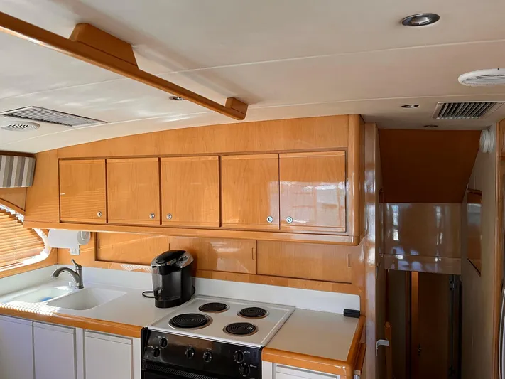 Satisfaction Yacht Photos Pics 1999 Bertram 60 Convertible yacht kitchen with wooden cabinets and modern appliances.