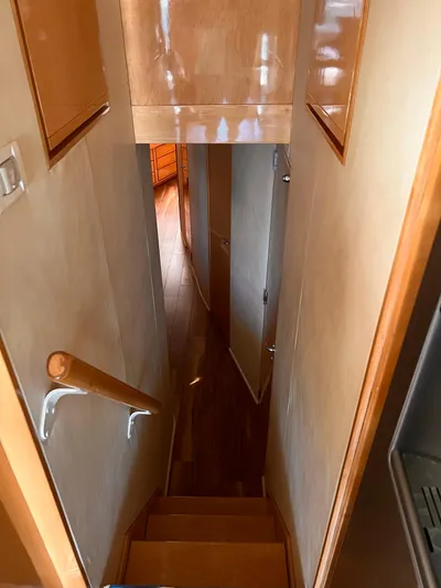Satisfaction Yacht Photos Pics Staircase inside a 1999 Bertram 60 Convertible yacht with wooden handrails and walls.