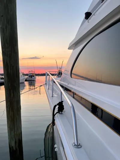 Satisfaction Yacht Photos Pics 1999 Bertram 60 Convertible yacht docked at sunset with calm waters.